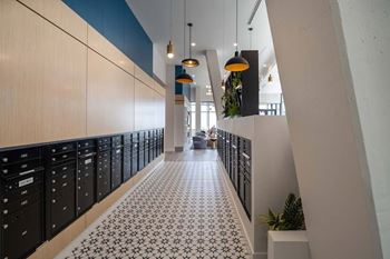 A long hallway with black lockers on the left and a tiled floor at Jayde Parkside Apartments, Washington DC