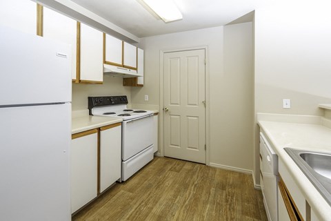 A kitchen with white appliances and wooden floors.at Sunset Ridge, West Jordan, UT