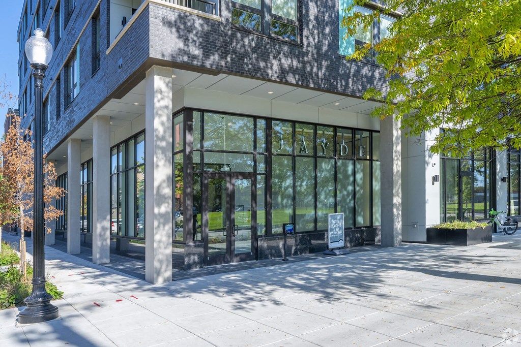 A modern building with a glass facade and a tree in front.