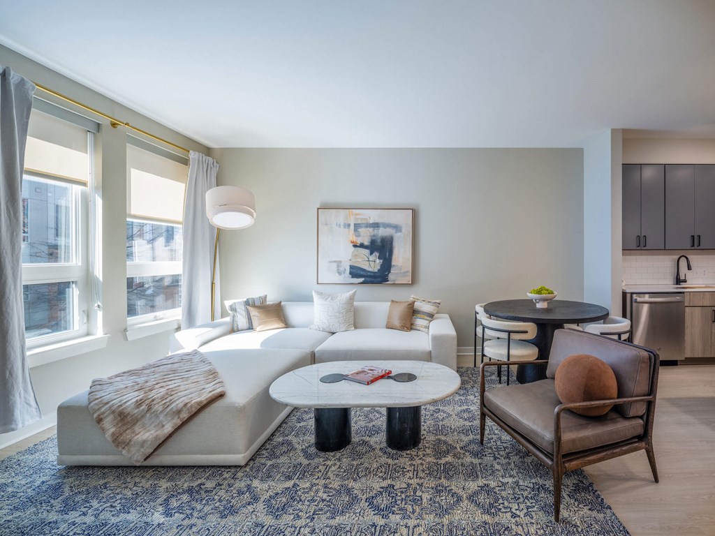 A living room with a white couch, a brown chair, and a blue rug at Jayde Parkside Apartments, Washington, DC, 20019