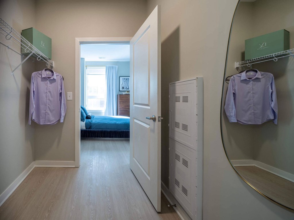 A hallway with a bedroom at the end and two shirts hanging up at Jayde Parkside Apartments, Washington, DC