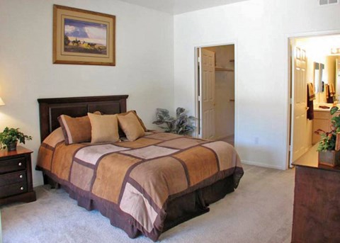 A bedroom with a bed, nightstand, and a painting on the wall.