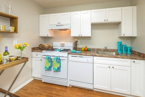A kitchen with white cabinets and a white stove top oven.