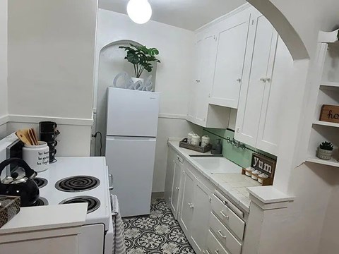 A kitchen with white cabinets and a black and white floor.