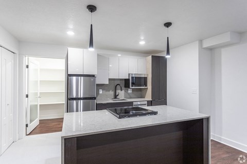 A modern kitchen with a stainless steel refrigerator and a dark countertop.