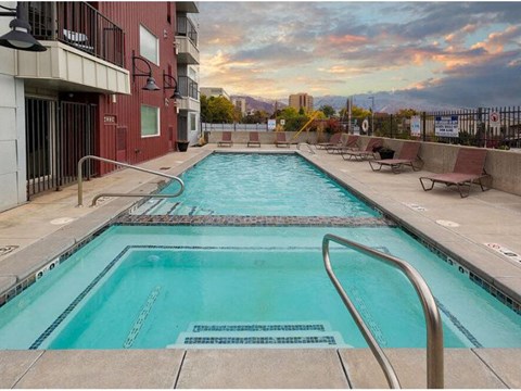 A swimming pool in a residential area with a sunset in the background.