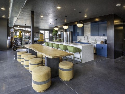 A modern kitchen with a long wooden table and green chairs.