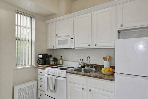 A white kitchen with a stove, microwave, and refrigerator.