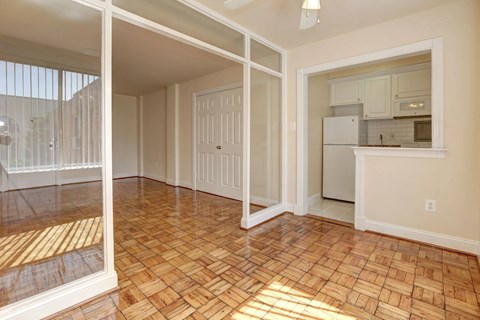 A room with a wooden floor and a kitchen in the background.