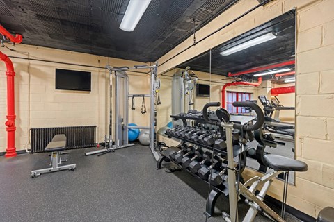 Fitness center with cable machine and dumbbells at Empire Apartments, Washington