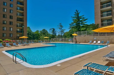 Outdoor swimming pool with lounge chairs and umbrellas at Remington Place Apartments, Fort Washington, MD 20744