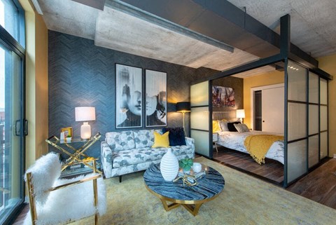 A modern living room with a grey couch and a yellow throw pillow.