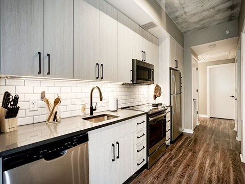 A kitchen with white cabinets and black appliances.