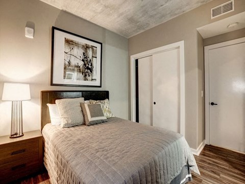 A bedroom with a bed, nightstand, and lamp.