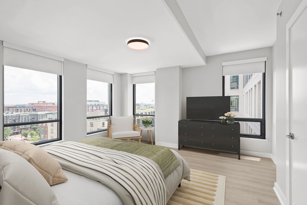 A bedroom with a large bed and a balcony overlooking the city.