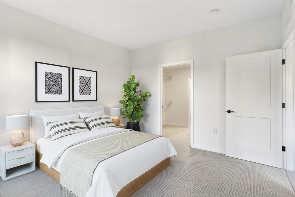 a white bedroom with a bed and a potted plant