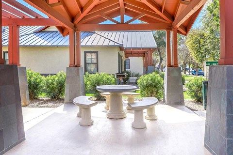 A pavilion with a table and chairs is surrounded by concrete pillars at Roosevelt Commons Apartments, Arizona, 85003