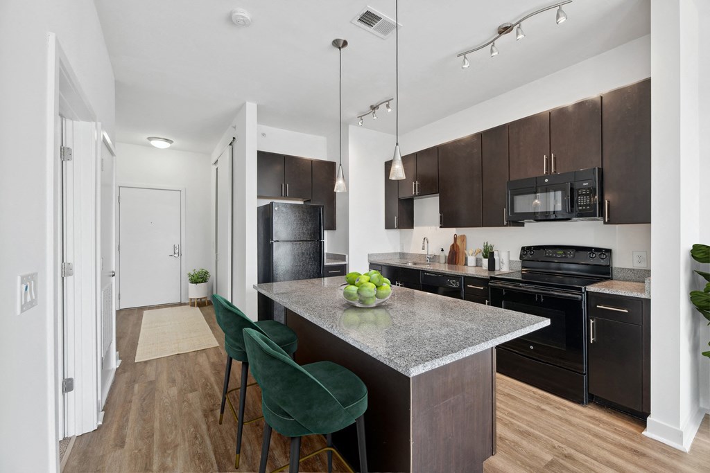 a kitchen with black appliances and a marble counter top with green chairs at Fort Totten Square, Washington DC, 20011