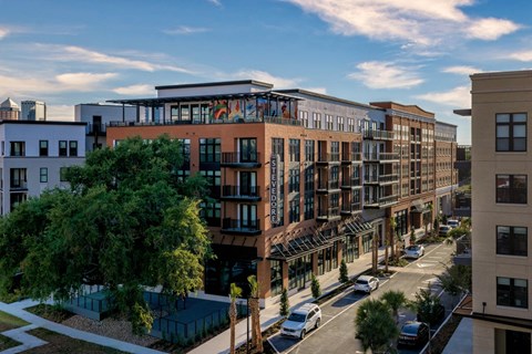 A street view of a row of modern buildings with cars parked on the street at The Stevedore Apartments in Tampa, FL 33605