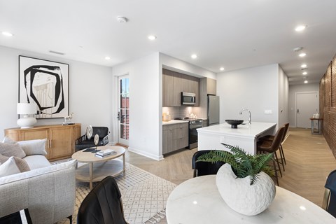 A modern living room with a grey sofa, a white coffee table, and a white dining table.