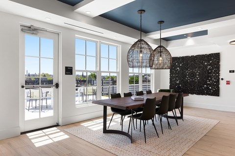 A dining room with a table and chairs and a view of the outside.