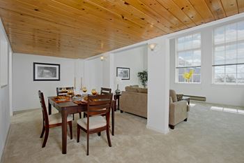 a dining room and living room with a wooden ceiling and a table and chairs at Tindeco Wharf, Baltimore, 21224