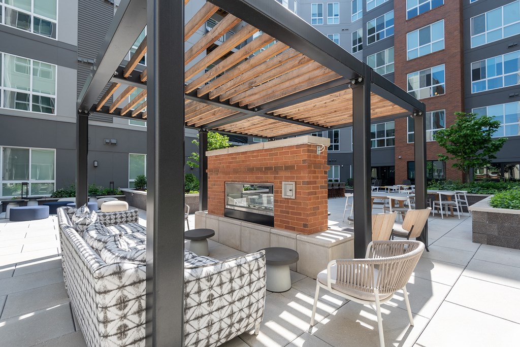a pergola with a fireplace and seating area in front of an apartment building at Vesta Parkside, Washington, DC, 20019