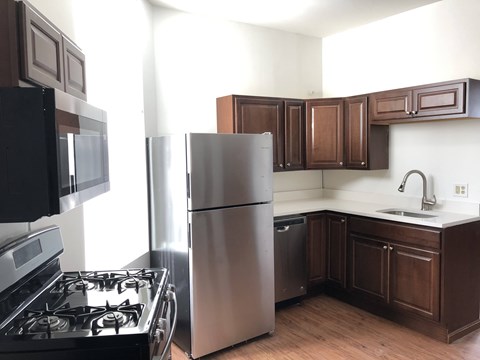 A kitchen with a black stove top oven, a silver refrigerator, and brown cabinets.