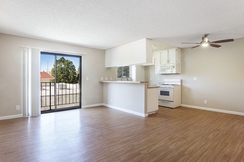 an empty living room and kitchen with a door to a balcony