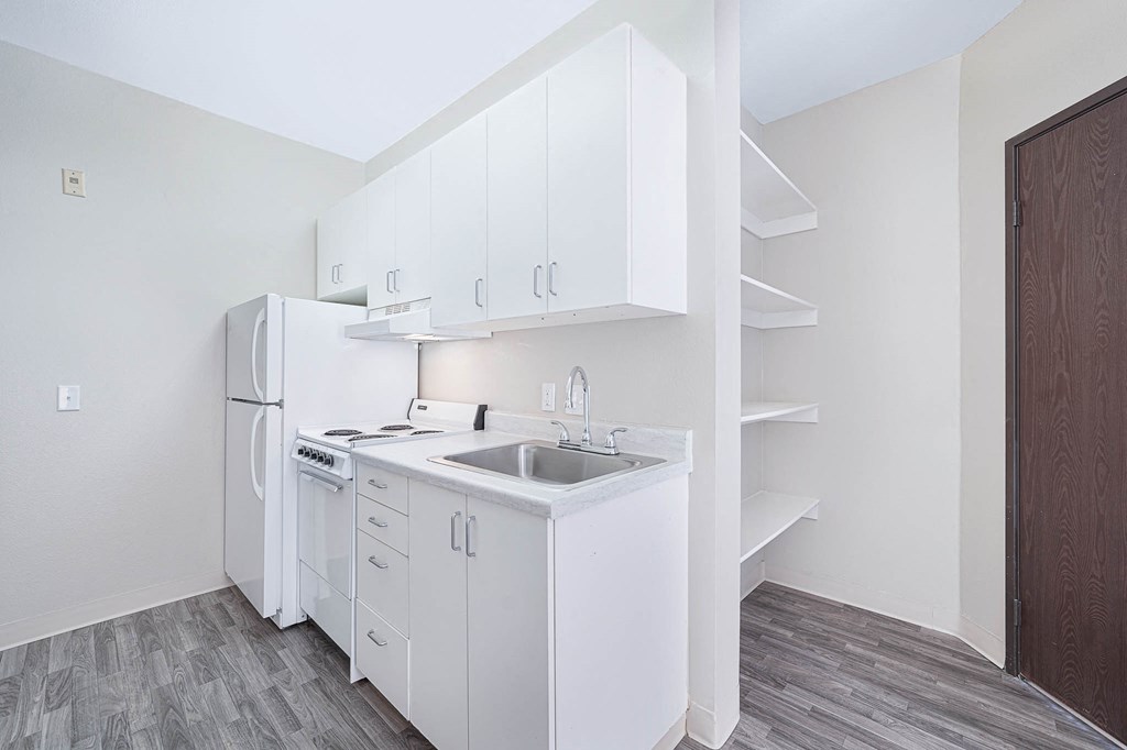 a white kitchen with a sink and a refrigerator
