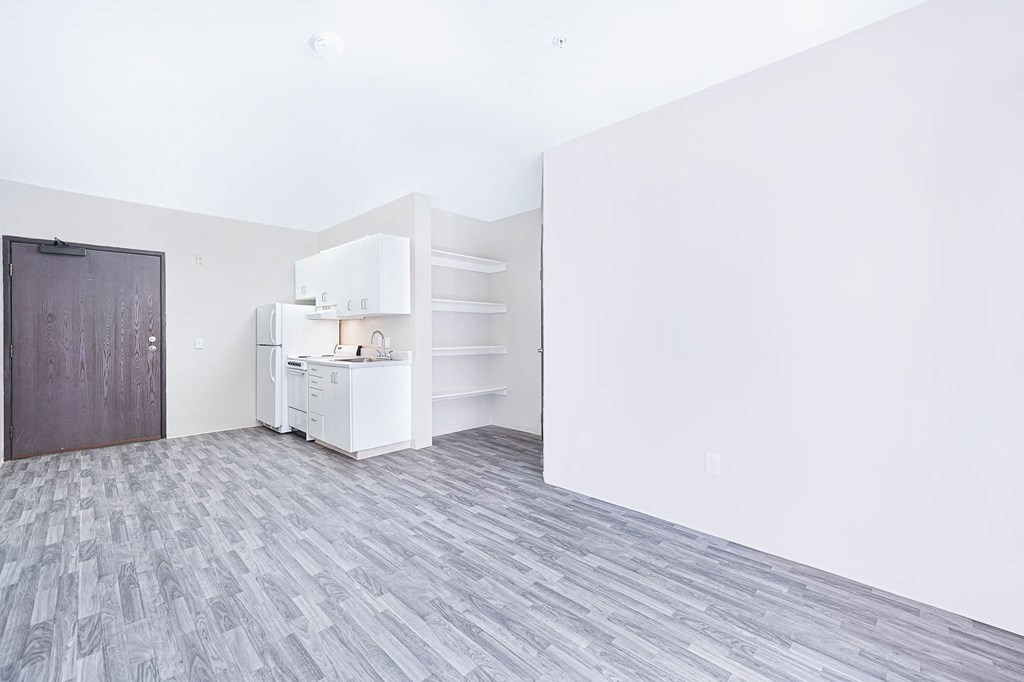 an empty room with a kitchen and a door