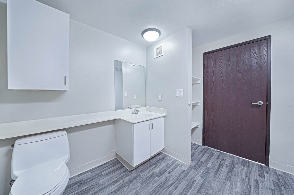 a white bathroom with a wooden door and a toilet and a sink
