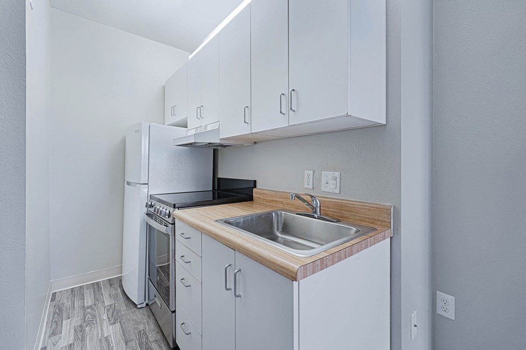 a kitchen with white cabinets and a sink and a refrigerator
