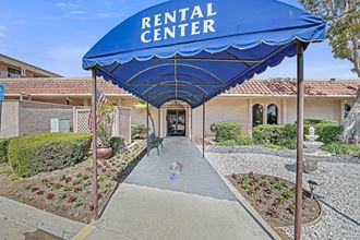 the entrance to the rental center with a blue canopy over the sidewalk and a dog