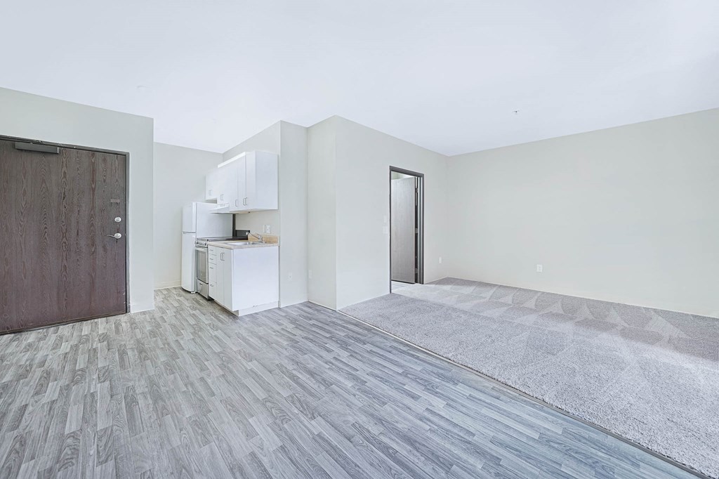 an empty living room with a door to a kitchen