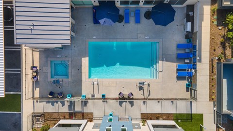 An outdoor pool with blue chairs and a small hot tub.