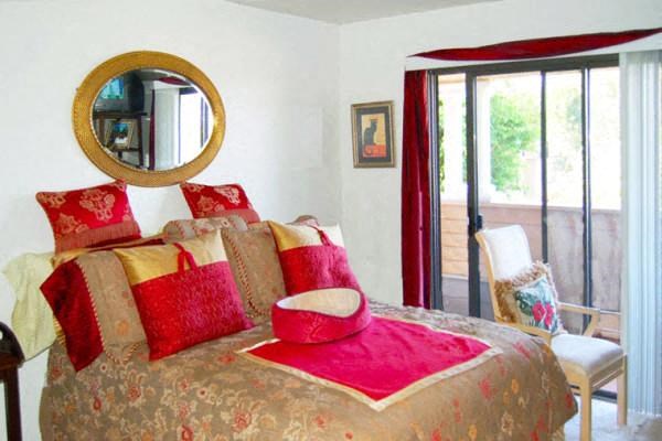 a bedroom with a bed with red pillows and a mirror