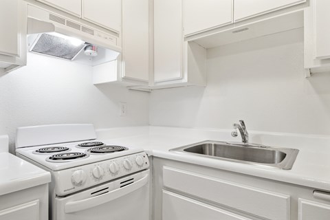 A white kitchen with a stove and sink.