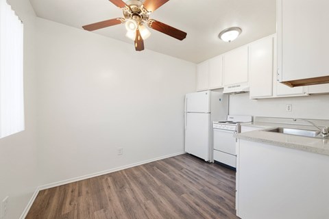 A kitchen with white cabinets and a wooden floor.