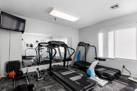 A home gym with a treadmill, exercise bike, and other equipment. at Whispering Fountains Lakewood, California
