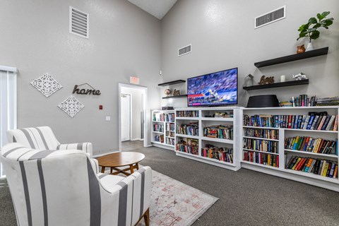 A living room with a large bookshelf filled with books and a flat screen TV mounted on the wall.