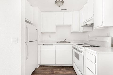 A white kitchen with a refrigerator, stove, and cabinets.