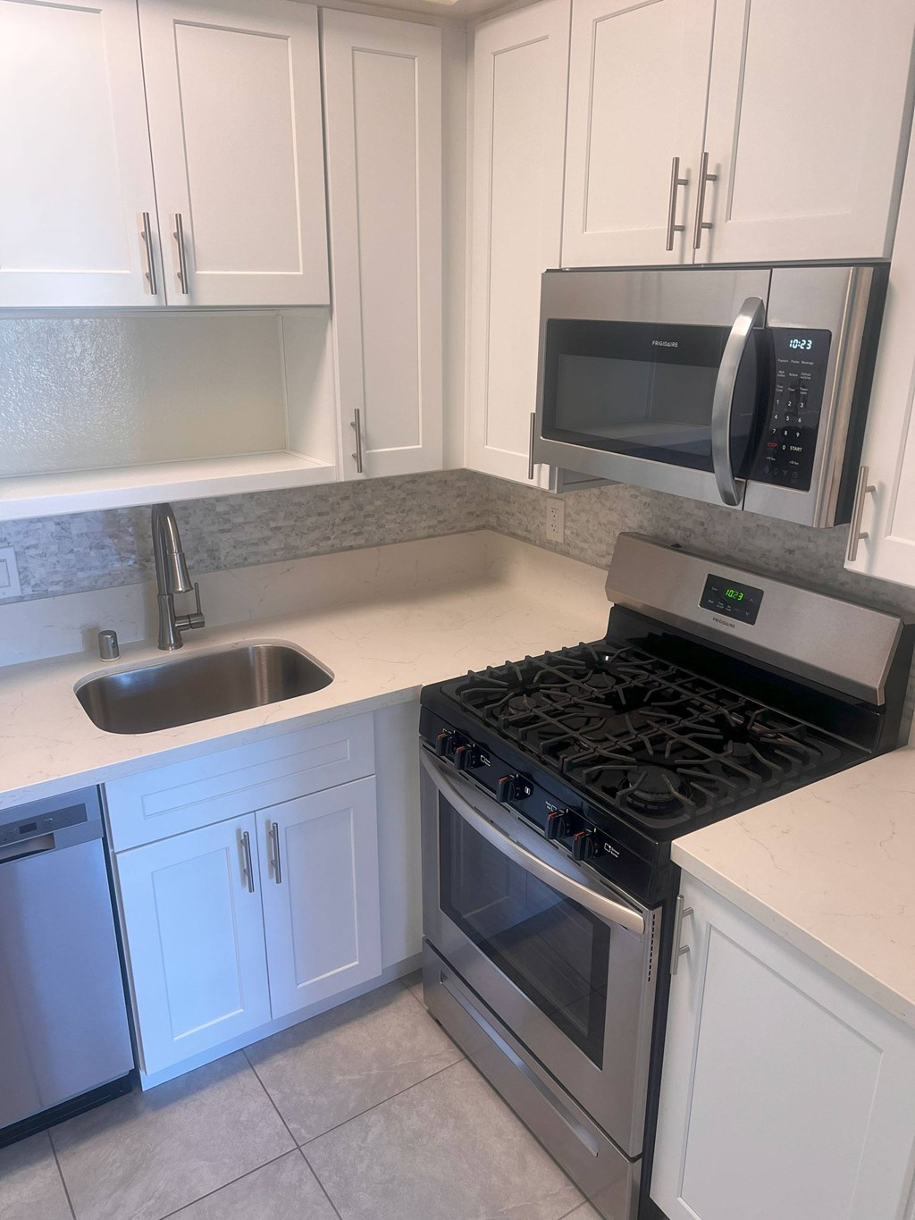 A kitchen with a stove, sink, and microwave.