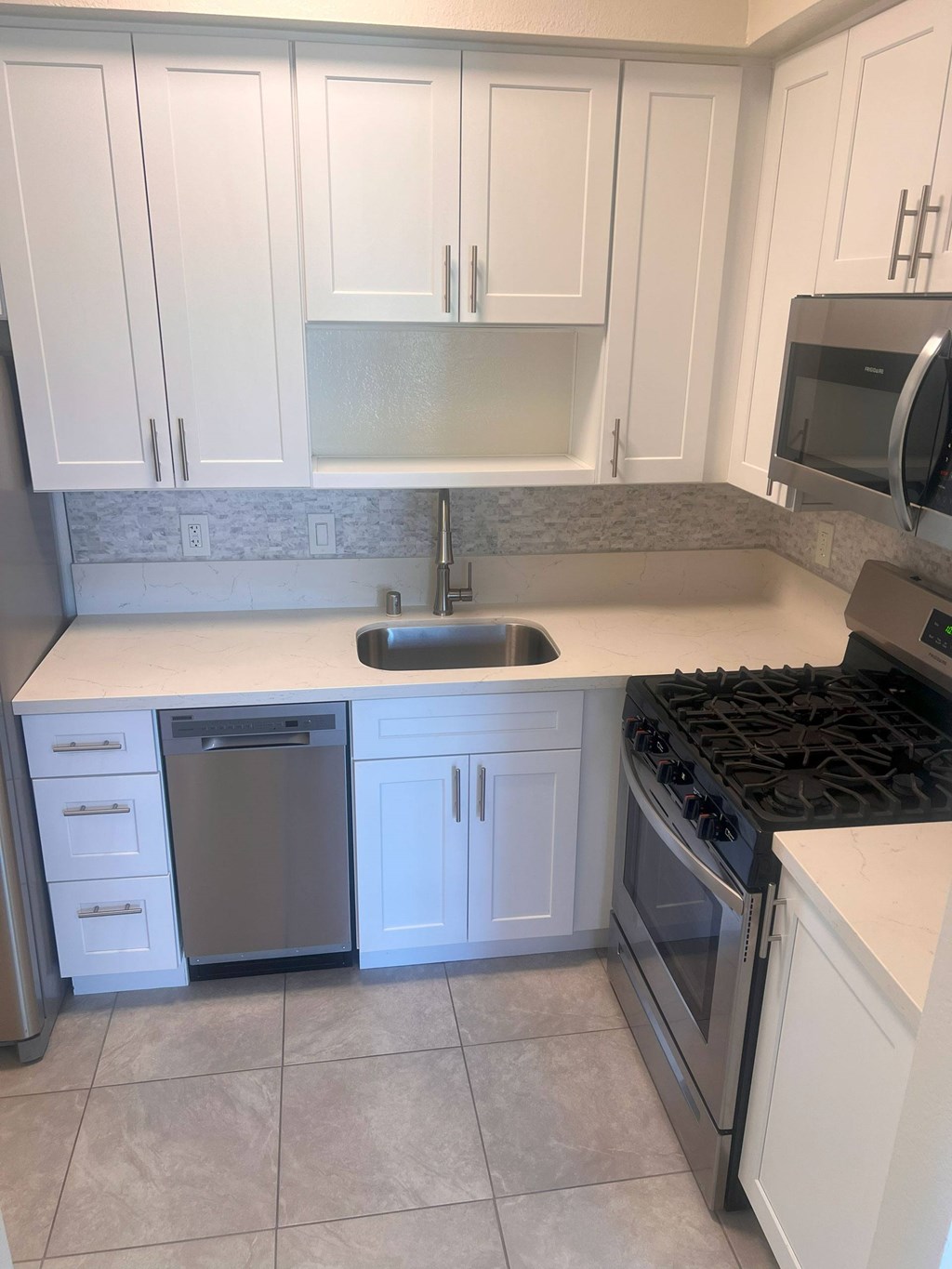 A kitchen with white cabinets and a black stove top.