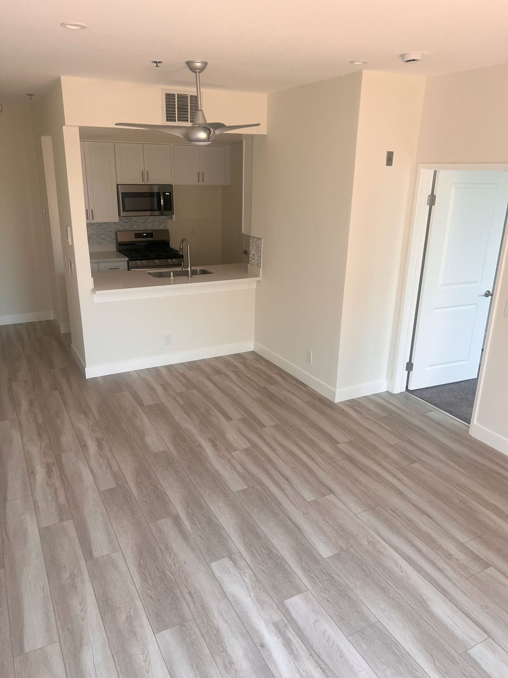 A room with a kitchenette and a fan.