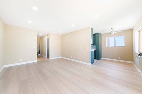 A spacious room with light wood flooring and a ceiling fan.