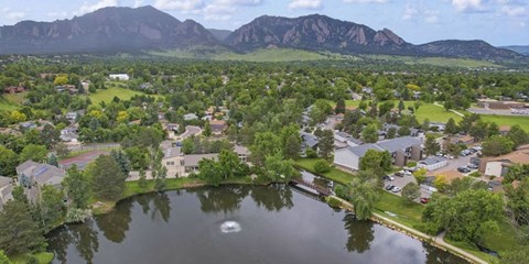 A serene lake surrounded by houses and trees with mountains in the distance.