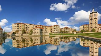Looking at Bell Tower Flats and other buildings of Adriatica, including the Bell Tower, from across the lake. The water is so smooth the reflection of everything is seen clearly in the water.