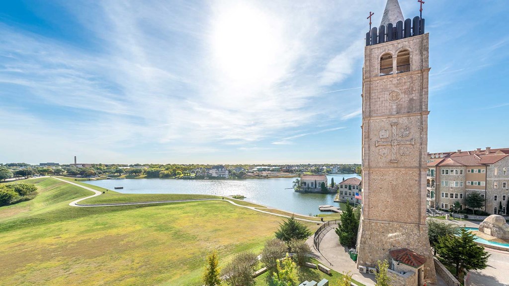 The Bell Tower stands tall on the right with an open field and the lake further beyond on the left.