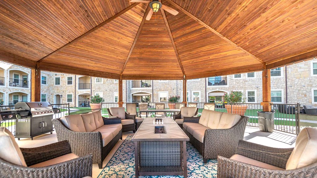 Under the gazebo in the courtyard at Bell Tower Reserve. Patio furniture sits around a coffee table. There is a grill to the left.